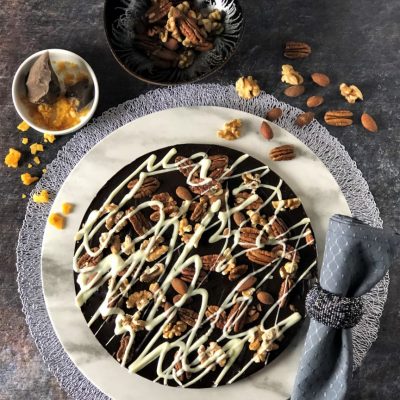 dark chocolate pizza with pecans almonds walnuts on white plate
