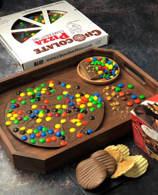 wooden tray with MM topped Chocolate Pizza and pizza box. Peanut Butter Wings in front.