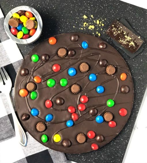 peanut butter cups and candies on dark chocolate pizza